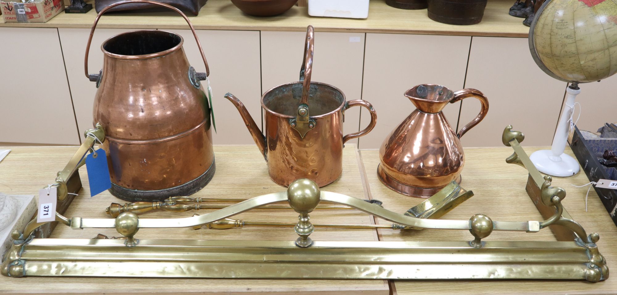 A late Victorian Art Nouveau brass fire kerb, length 132cm, a set of three Victorian fire brasses, a Dutch copper water can and a coppe